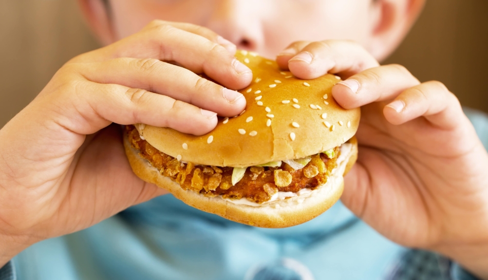 Bambino che mangia un panino con hamburger