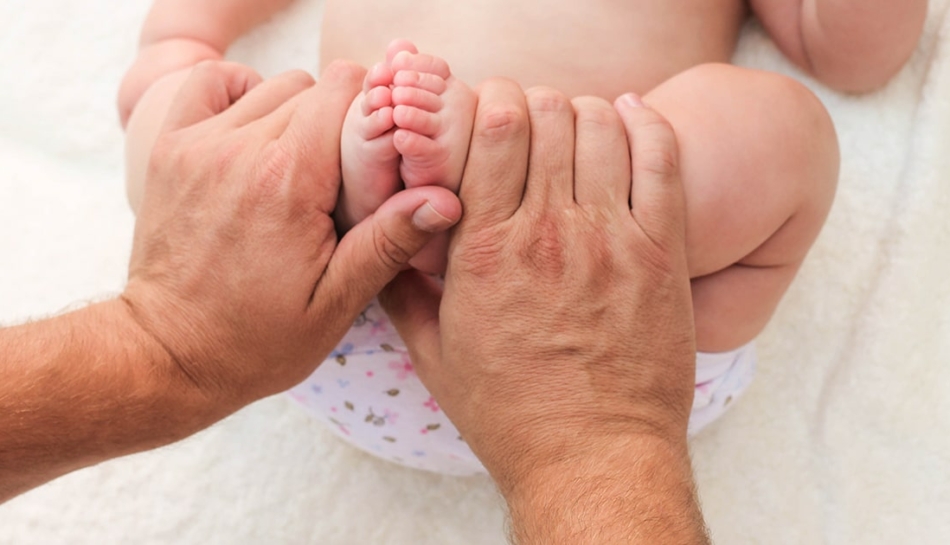 Piedi di neonato tenuti tra le mani di un genitore