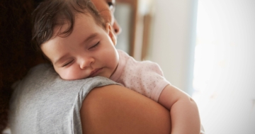 Bambino che dorme in braccio alla mamma