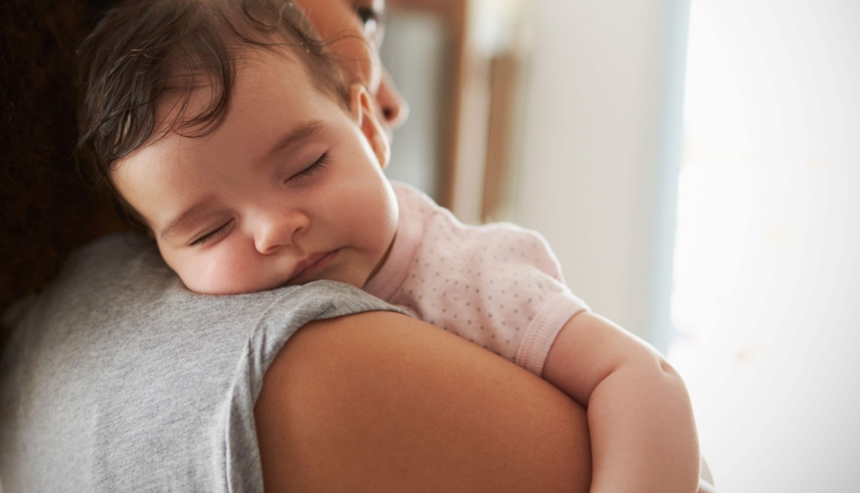 Bambino che dorme in braccio alla mamma