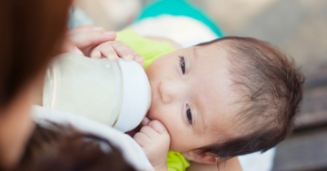 Bambino che beve dal biberon un sostituto del latte materno