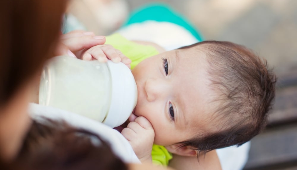 Bambino che beve dal biberon un sostituto del latte materno