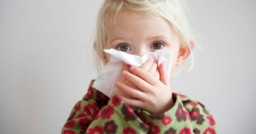 Bambina con il raffreddore che si soffia il naso