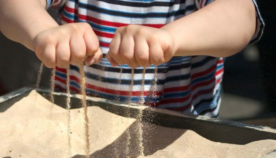 Mani di bambino che gioca con la sabbia come previsto dalla Sand play theory