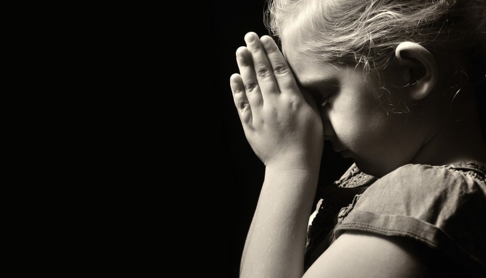 Bambina con le mangi giunte in preghiera