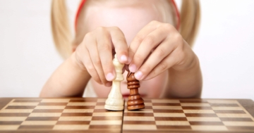 Little girl moving chess and learning the rules