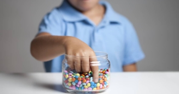 bambino mangia caramelle con rischi obesità infantil