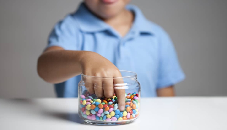 bambino mangia caramelle con rischi obesità infantil