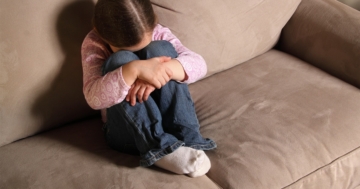 The little girl curled up on the couch