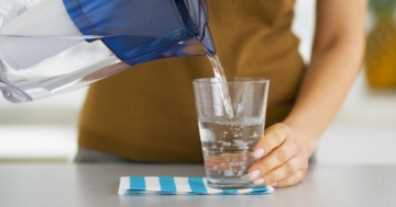 Donna che versa l'acqua da una caraffa filtrante