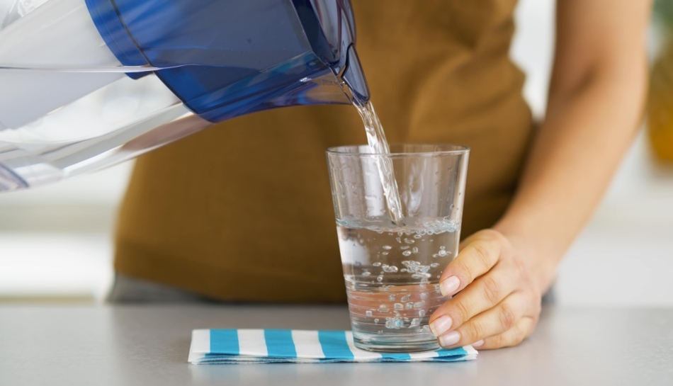 Donna che versa l'acqua da una caraffa filtrante