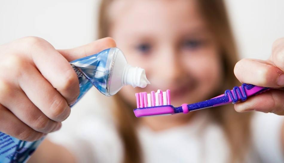 Bambina che mette del dentrificio sullo spazzolino