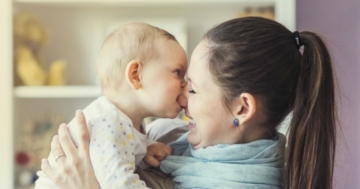 Bambino che morde il naso della mamma