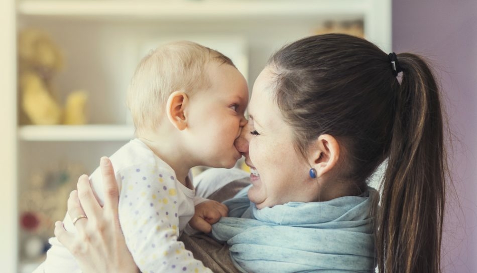 Bambino che morde il naso della mamma