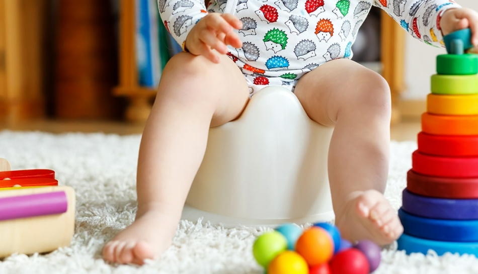 Primo piano di gambe di bambino senza pannolino seduto sul vasino