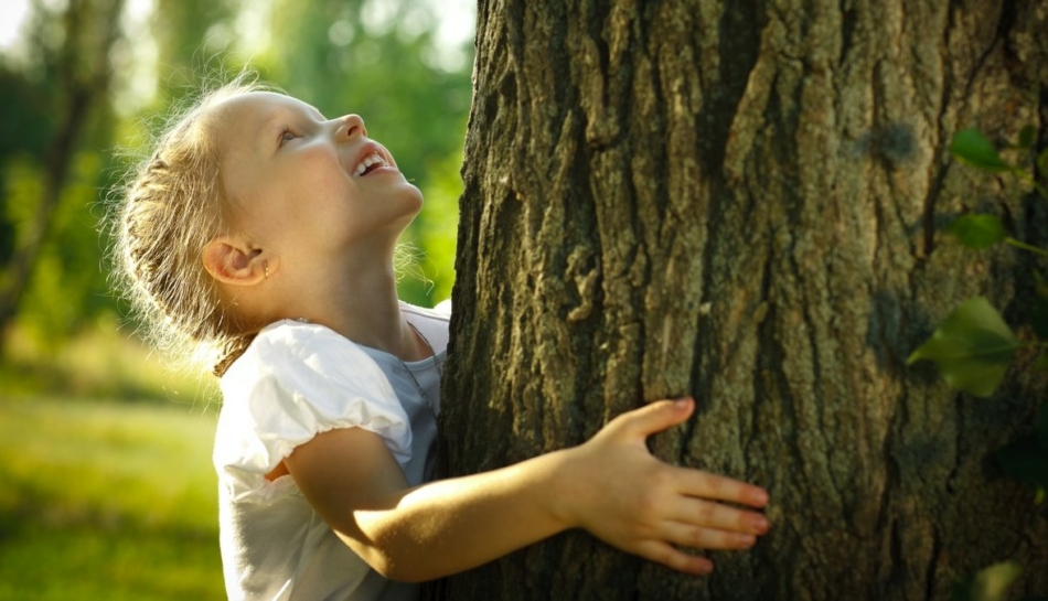 Bambina nella natura abbraccia un albero