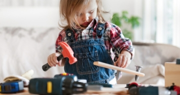 Little girl plays with toy work tools