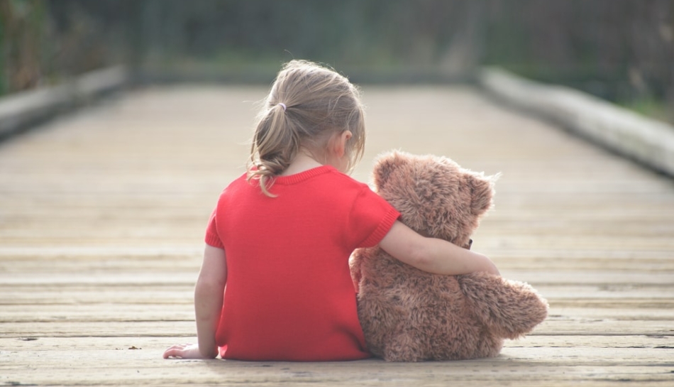 Bambina di spalle con il suo orsacchiotto