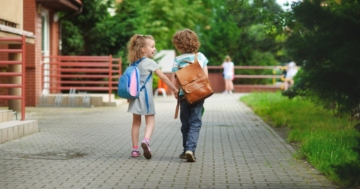 Bambini vanno a scuola tenendosi per mano