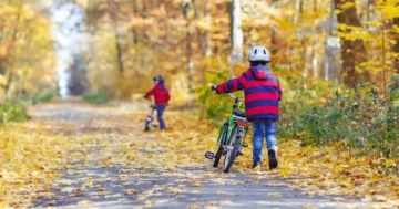 Bambini che si muovono a piedi portando la bici