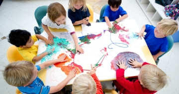 Bambini di un asilo che cooperano nel disegno