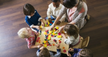 Bambini all'asilo intorno a un tavolo in una classe eterogenea