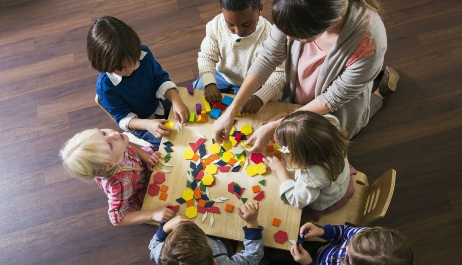 Bambini all'asilo intorno a un tavolo in una classe eterogenea