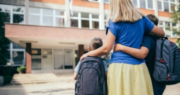 Mamma con due bambini all'ingresso a scuola