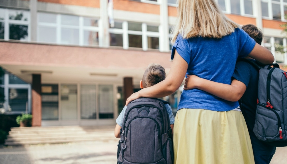 Mamma con due bambini all'ingresso a scuola