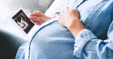 Primo piano della pancia di una donna in gravidanza che guarda un'ecografia