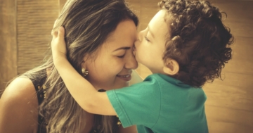 Bambino che con empatia bacia la madre sulla fronte