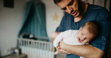 Padre culla il bambino dolcemente, evitando rischi di sindrome del bambino scosso