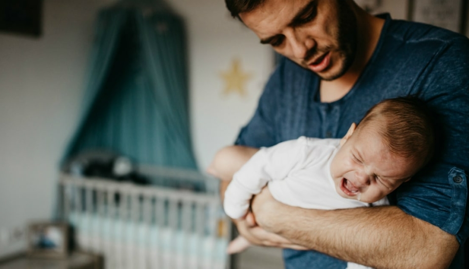 Padre culla il bambino dolcemente, evitando rischi di sindrome del bambino scosso