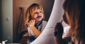 Bambino che si lava i denti allo specchio