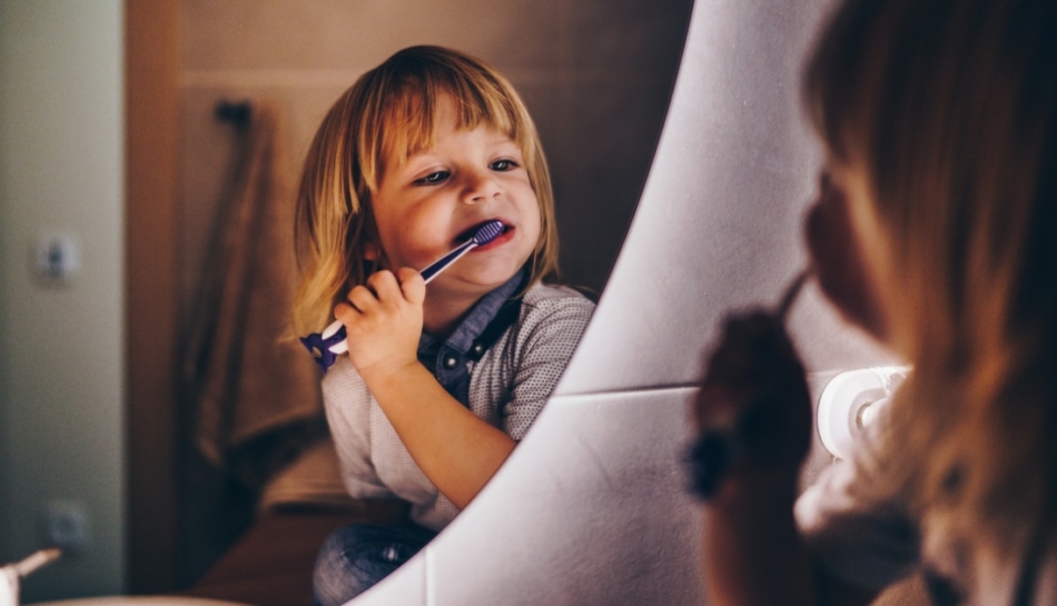 Bambino che si lava i denti allo specchio