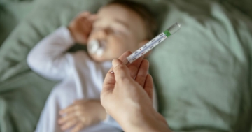Bambino piccolo cui viene misurata la febbre per la quinta malattia