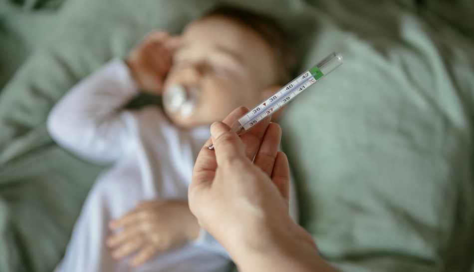 Bambino piccolo cui viene misurata la febbre per la quinta malattia