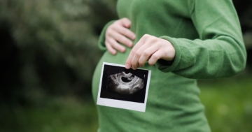 Donna in gravidanza che tiene l'ecografia del bambino davanti alla pancia