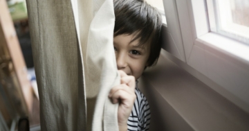 Child hiding behind a curtain for privacy