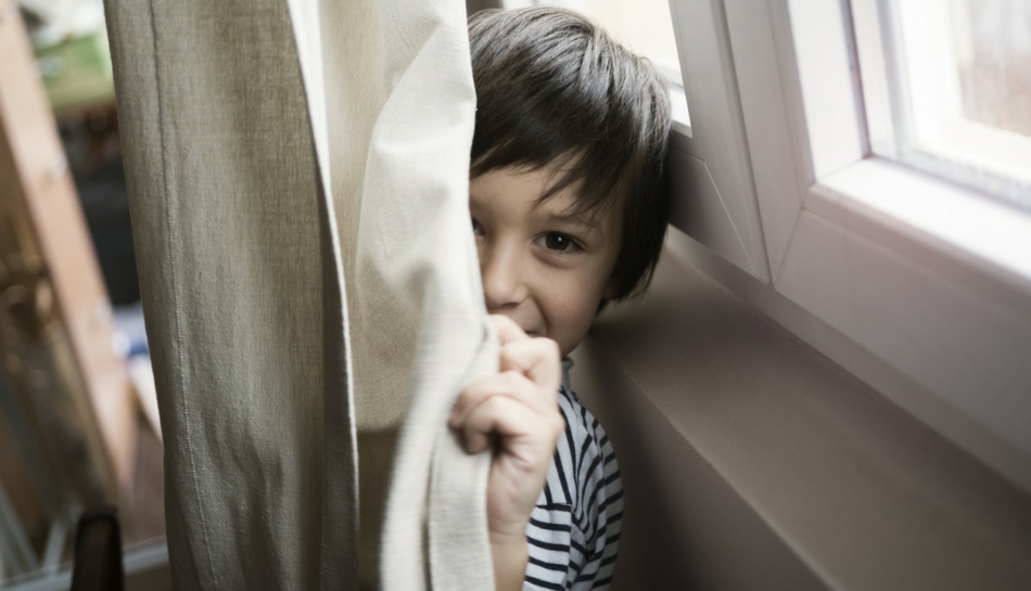 Bambino che per privacy si nasconde dietro a una tenda