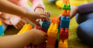 Hands of children playing with building blocks in kindergarten