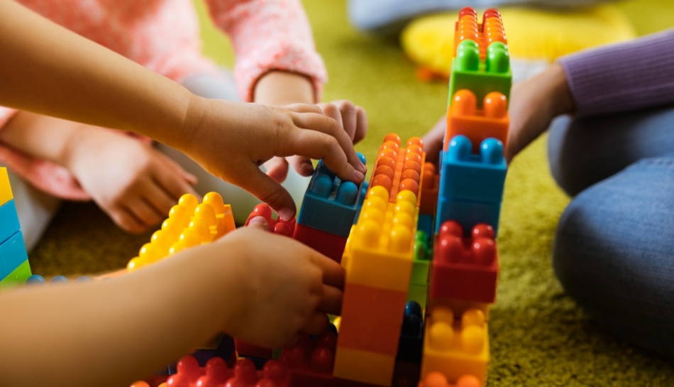 Mani di bambini che giocano con le costruzioni all'asilo nido