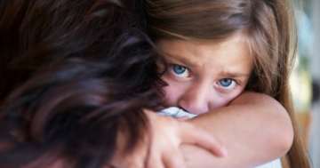 Close up of a little girl hugging her mother tightly