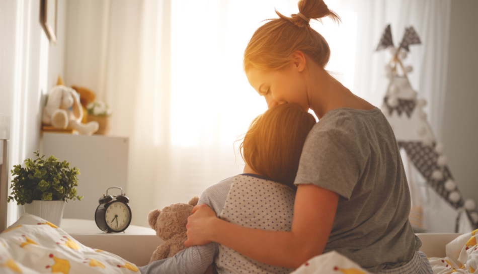 Mamma e bambina di schiena abbracciate sul letto