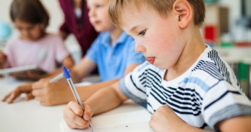 Bambino a scuola utilizza una penna