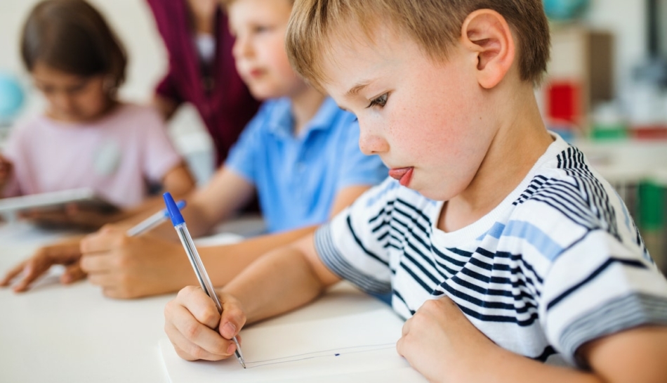 Bambino a scuola utilizza una penna