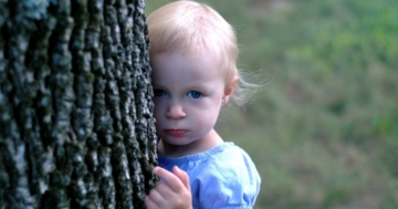 Bambina si nasconde dietro un albero