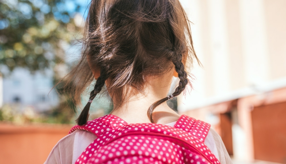 primo piano di bambina di spalle con zainetto