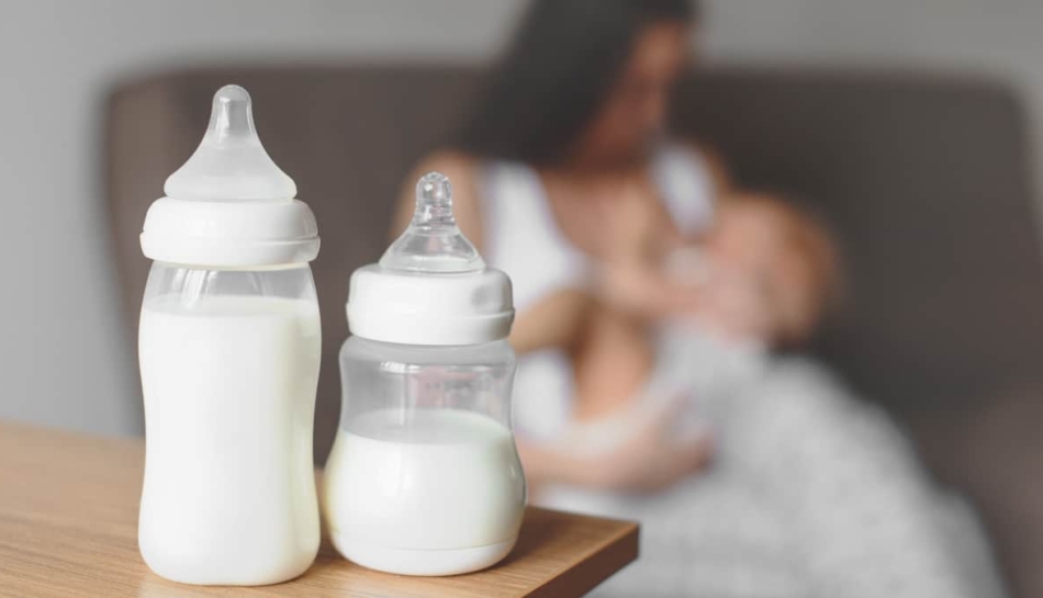 Latte artificiale nei biberon e mamma che allatta il proprio bambino