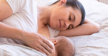 mamma che guarda il suo neonato sdraiata accanto a lui